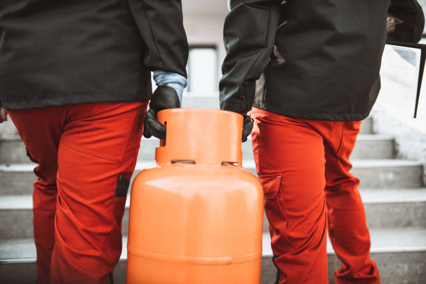 liquefied gas storage workers carrying gas cylinder on staircase